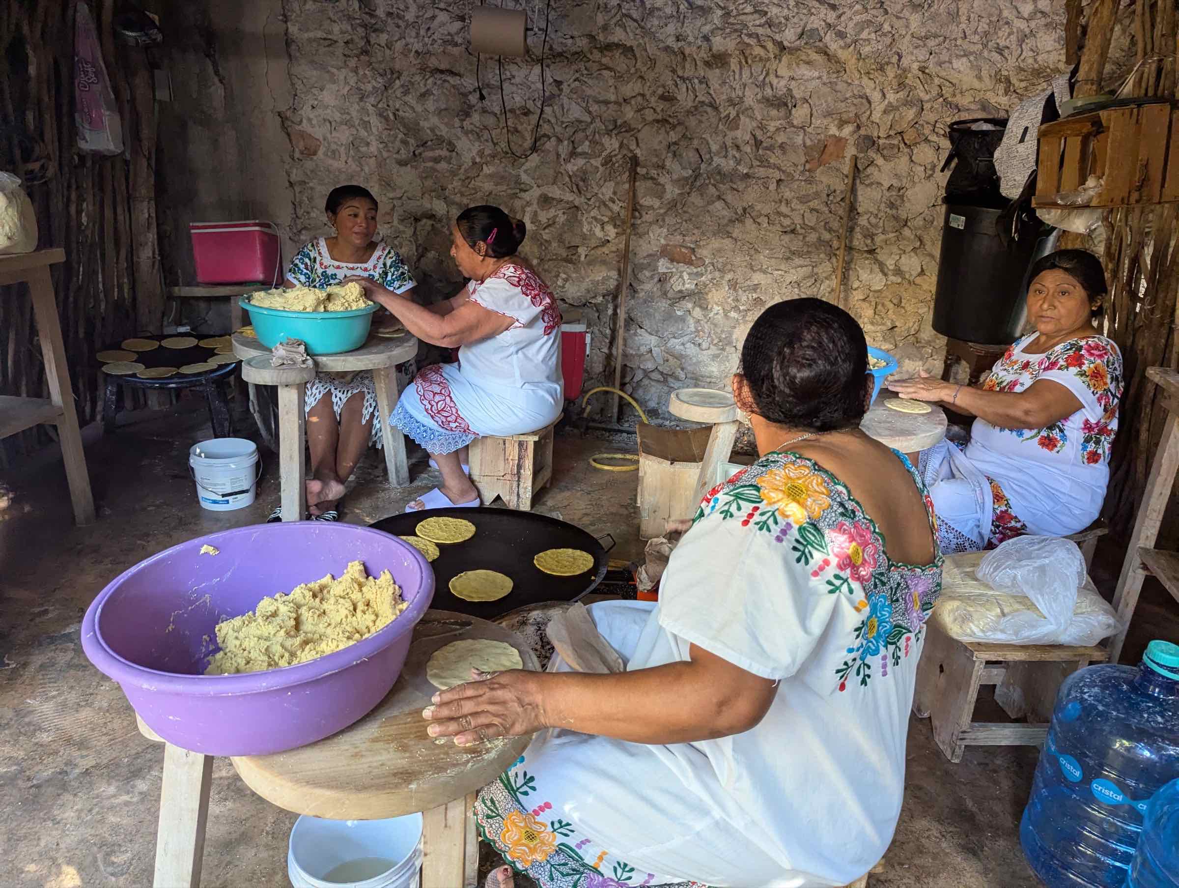 Mujeres con hipil bordado haciendo tortillas a mano en una cocina tradicional de Yucatán